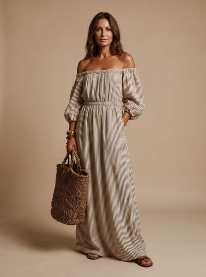 Damesmodel in bohemian gestreepte off-shoulder maxi-jurk, volledig in beeld.